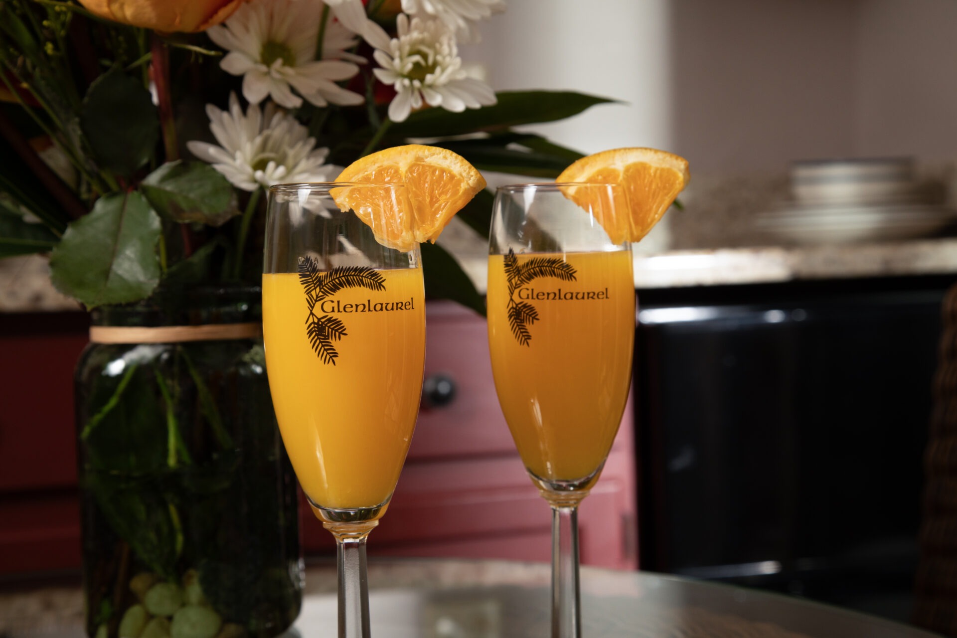 Two Glenlaurel glasses with mimosas, complete with an orange on the rim.