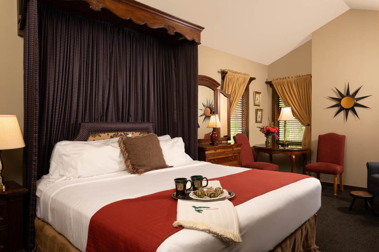 Picture of the bed in the Mackenzie Royal Suite at Glenlaurel, with two mugs and chocolate covered strawberries.