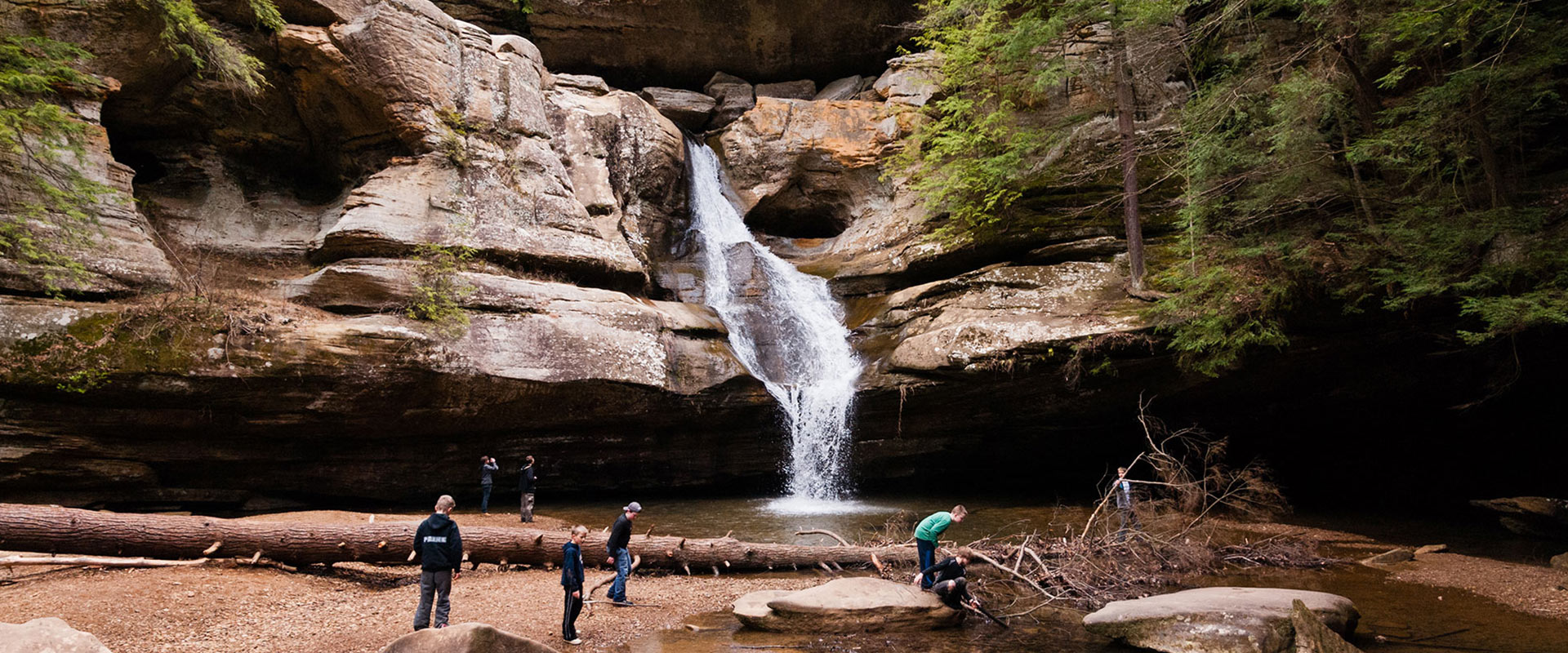 People hiking near a waterfall.